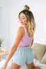 Blonde girl models the Namaste Home Loungewear Collection set for Scarlette The Label, an online fashion boutique for women. The set includes a soft lilac crop top and baby blue loungewear shorts. Sold separately.