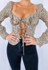 Blonde girl models a leopard print tie blouse for Scarlette The Label, an online fashion boutique for women. The long sleeve leopard blouse is paired with dark denim jeans.