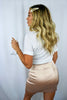Blonde girl models a plain white tee and a blush satin-style asymmetrical mini skirt for Scarlette The Label, an online fashion boutique for women.