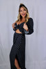Blonde girl models a black, flowy matching set for Scarlette The Label, an online fashion boutique for women. The matching set includes a black crop tie top and black flare, flowy pants. Each sold separately.