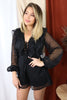 Blonde girl models mesh long sleeve ruffled romper in black for Scarlette The Label, an online fashion boutique for women.