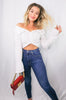 Load image into Gallery viewer, Blonde girl models an off the shoulder long sleeve button down shirt in white for Scarlette The Label, an online fashion boutique for women. The white button down shirt is tied as a crop top. Paired with dark denim jeans and a red and gold clutch. 