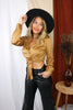 Load image into Gallery viewer, Blonde girl models outfit for Scarlette The Label, an online fashion boutique for women. The blouse is a long sleeve suede crop top blouse in the color camel. Pants are faux leather pants. Paired with wide brimmed black hat.
