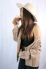 Load image into Gallery viewer, Brunette girl models buttoned corduroy jacket in the color tan for Scarlette The Label, an online fashion boutique for women. The corduroy jacket is an oversized street style jacket. Paired with a black crop top, dark denim jeans, and a wide-brimmed rancher hat.