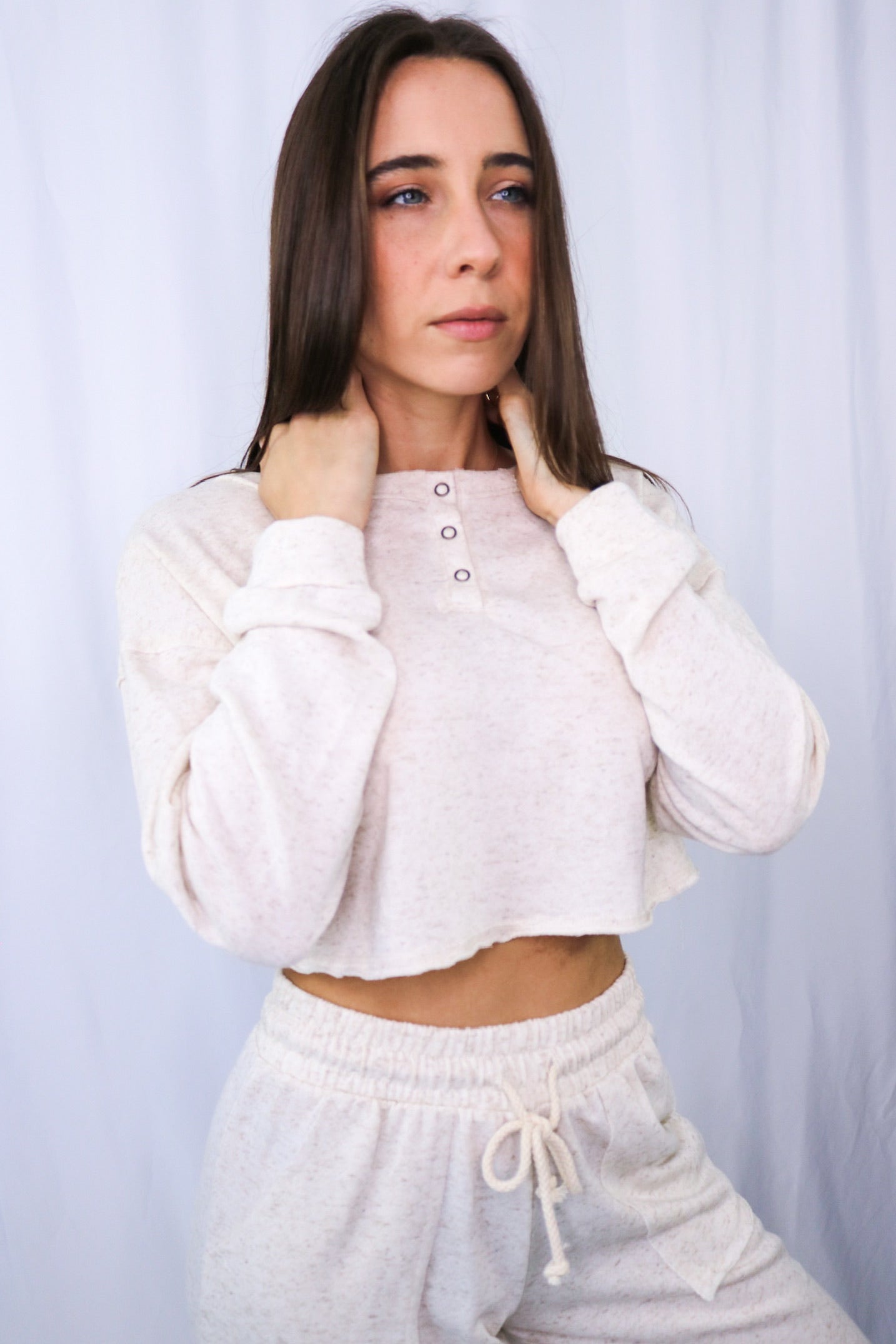 Brunette models long sleeve and pant linen loungewear set in color: natural (ivory) for Scarlette The Label, an online fashion boutique for women.