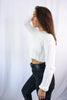 Load image into Gallery viewer, Brunette girl models ivory (white) knitted crop sweater for Scarlette The Label, an online fashion boutique for women. THe knitted crop sweater is very soft and breathable. Paired with dark denim jeans.