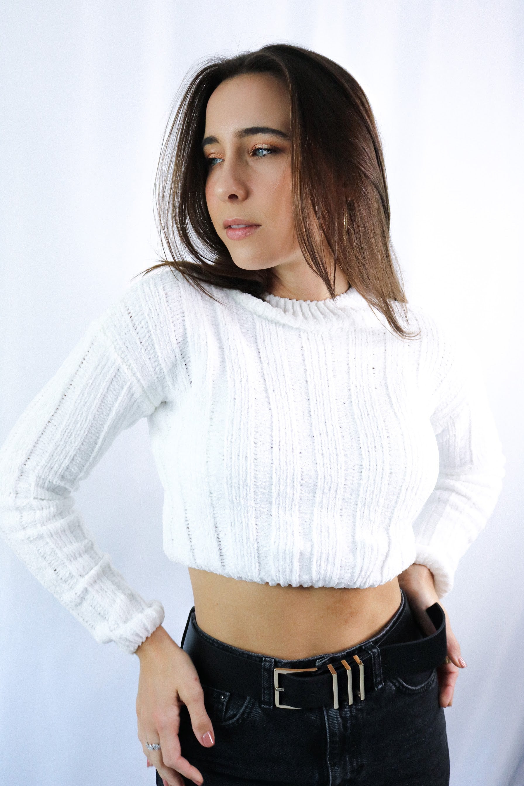 Brunette girl models ivory (white) knitted crop sweater for Scarlette The Label, an online fashion boutique for women. THe knitted crop sweater is very soft and breathable. Paired with dark denim jeans.