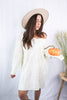 Load image into Gallery viewer, Brunette girl models a mid-length cable knit sweater dress in the color ivory for Scarlette The Label, an online fashion boutique for women. Paired with a beige wide-brimmed rancher hat.