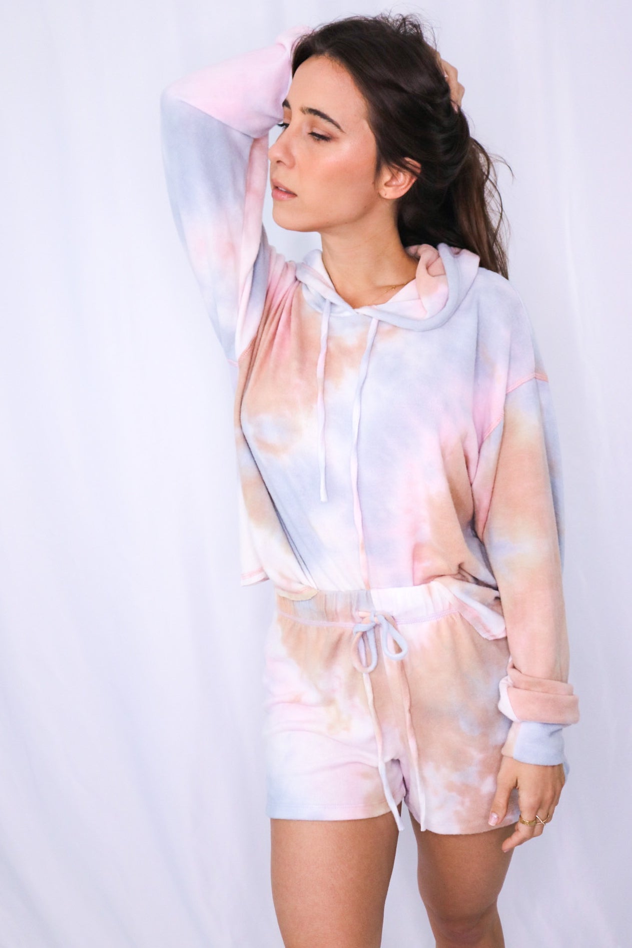 Brunette models long sleeve hoodie tie dye loungewear short set for Scarlette The Label, an online fashion boutique for women.