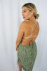 Load image into Gallery viewer, Blonde girl models a green crossback mini dress for Scarlette The Label, an online fashion boutique for women. The mini dress is a scrunched mini dress with floral details, spaghetti straps, and a plunging crossback design in the back.