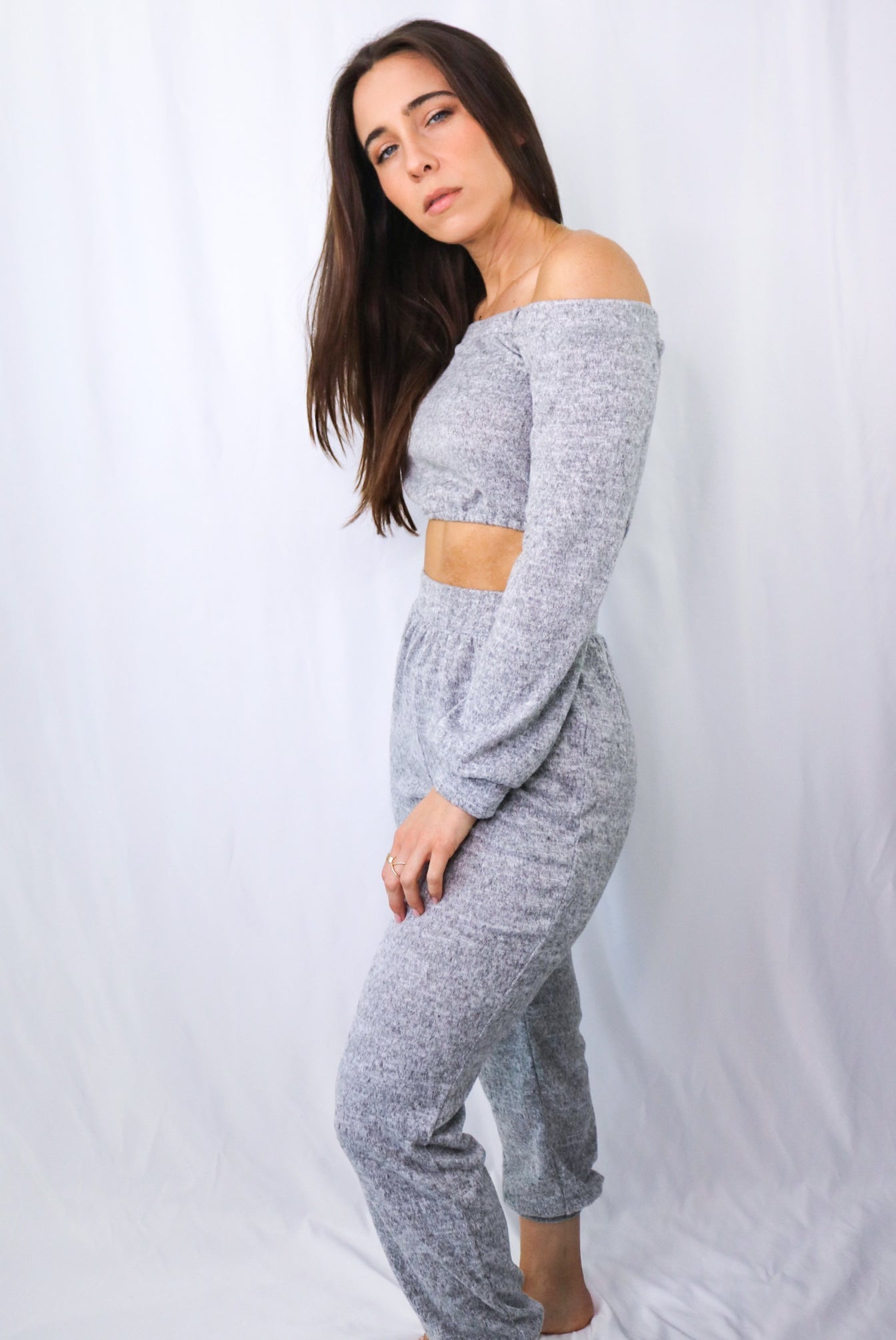 Brunette models off the shoulder long sleeve and pant loungewear set in heather gray for Scarlette The Label, an online fashion boutique for women.
