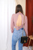 Load image into Gallery viewer, Brunette girl models high neck open back blouse in mauve for Scarlette The Label, an online fashion boutique for women. Paired with blue light wash denim jeans and a gucci purse.