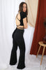 Brunette models outfit for Scarlette the Label, an online fashion boutique for women. Wears an open back black crop top and flare wide leg tie pants in black. Paired with wide brim rancher hat.