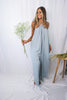 Blonde girl models a hi lo flowy, boxy jumpsuit in the color Gray for Scarlette The Label, an online fashion boutique for women.