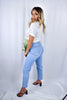 A blonde girl modeling a a plain white tee and light wash denim boyfriend jeans for Scarlette The Label, an online fashion boutique for women. Paired with black heels.