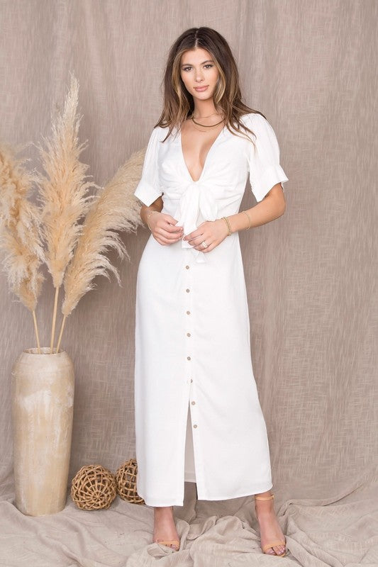 Short Sleeve Puff Sleeve buttoned maxi dress in white from Scarlette The Label, an online fashion boutique for women. Paired with gold hoops, gold clutch, and gold shoes.