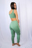 Load image into Gallery viewer, Brunette models matching jogger pant set in color: sage for Scarlette The Label, an online fashion boutique for women. Matching set comes with sage sports bra and matching joggers.