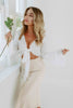 Load image into Gallery viewer, Blonde girl models a flared sleeve tie top in the color white and an ivory mid-length satin skirt for Scarlette The Label, an online fashion boutique for women. 
