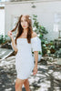 Load image into Gallery viewer, Brunette girl models white ruched mini dress with puff sleeves for Scarlette The Label, an online fashion boutique for women. White mini dress can be worn off the shoulders or regular.