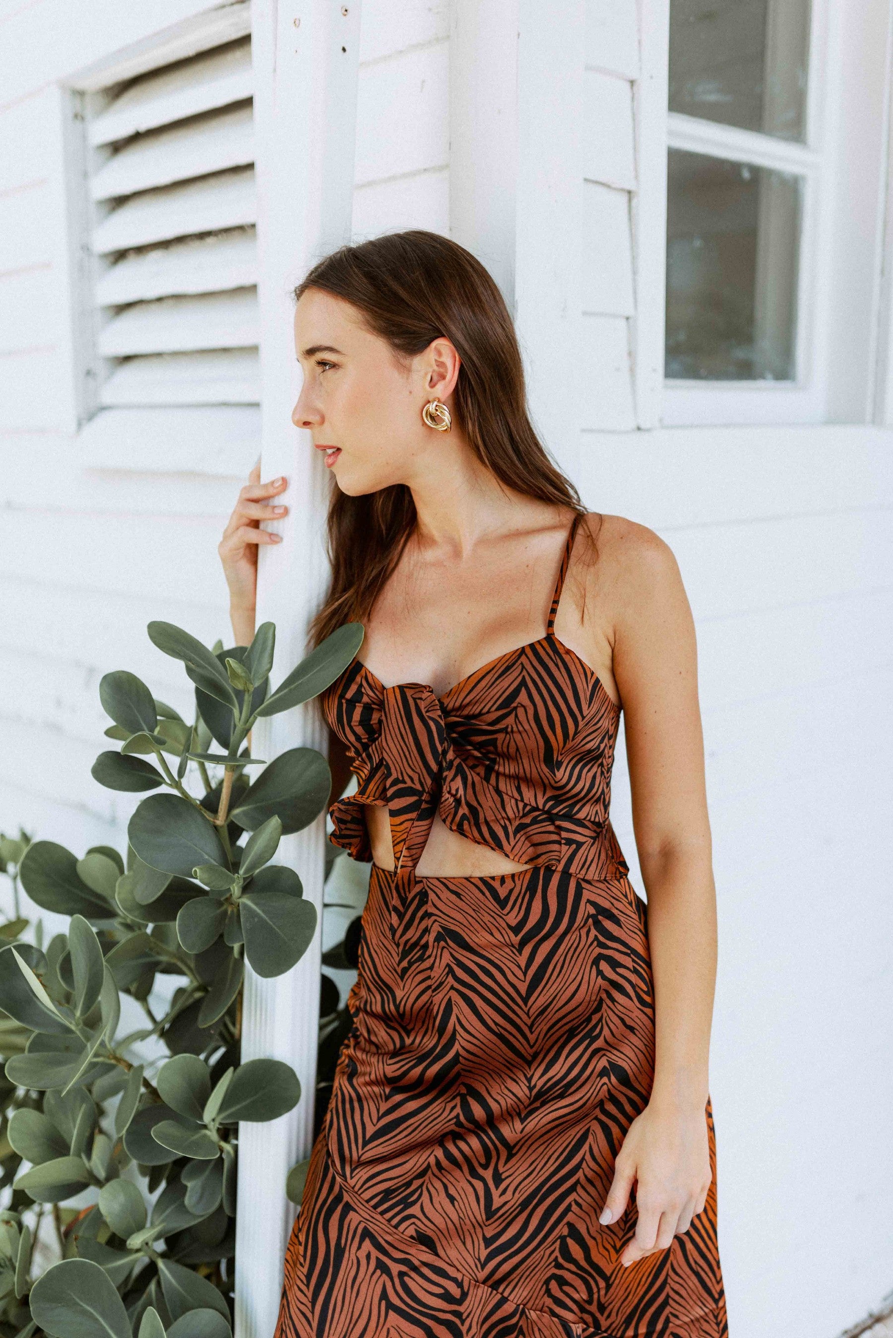 Brunette girl models an animal print maxi skirt set in brown and black. The matching maxi skirt set comes with a spaghetti strap crop top and long, flowy maxi skirt.