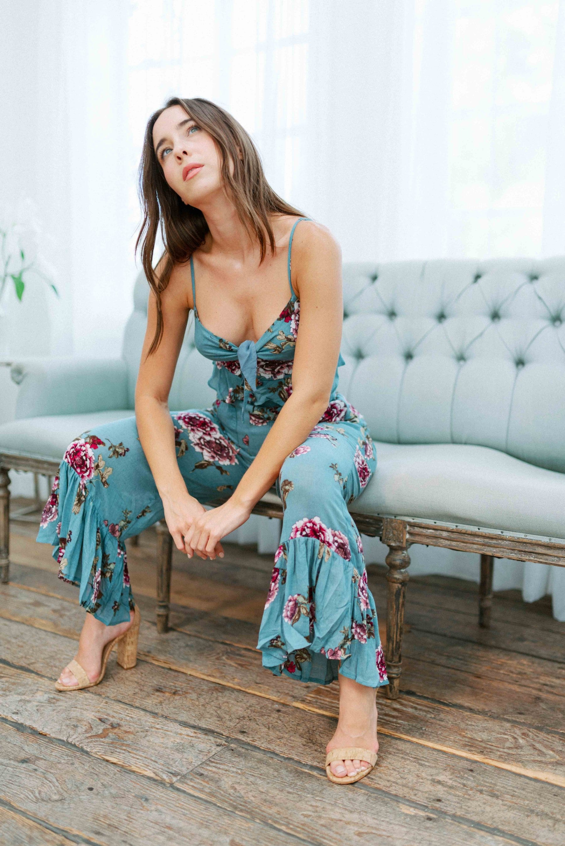 Brunette girl models a matching floral pant set (co-ord) for Scarlette The Label, an online boutique for women. The pant set is blue and has floral details. The crop top is a blue spaghetti strap tank top and the pants are blue flare pants. Paired with nude heels.