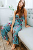 Load image into Gallery viewer, Brunette girl models a matching floral pant set (co-ord) for Scarlette The Label, an online boutique for women. The pant set is blue and has floral details. The crop top is a blue spaghetti strap tank top and the pants are blue flare pants. Paired with nude heels.