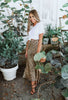 Load image into Gallery viewer, Blonde girl models midi skirt in leopard print for Scarlette The Label, an online fashion boutique for women. Midi leopard print skirt paired with a plain white tee and black heels.
