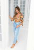 Load image into Gallery viewer, Blonde girl models a quarter sleeve floral crop top in the color Squash Flower for Scarlette The Label, an online fashion boutique for women. Paired with light wash denim boyfriend jeans.