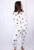 Brunette models long sleeve and long pant starry loungewear set in white with black stars for Scarlette The Label, an online fashion boutique for women.