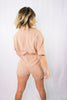 Load image into Gallery viewer, Blonde girl models tan collared romper for Scarlette The Label, an online fashion boutique for women. The romper is short sleeve and has a plunging collared neckline and adjustable waist strings.